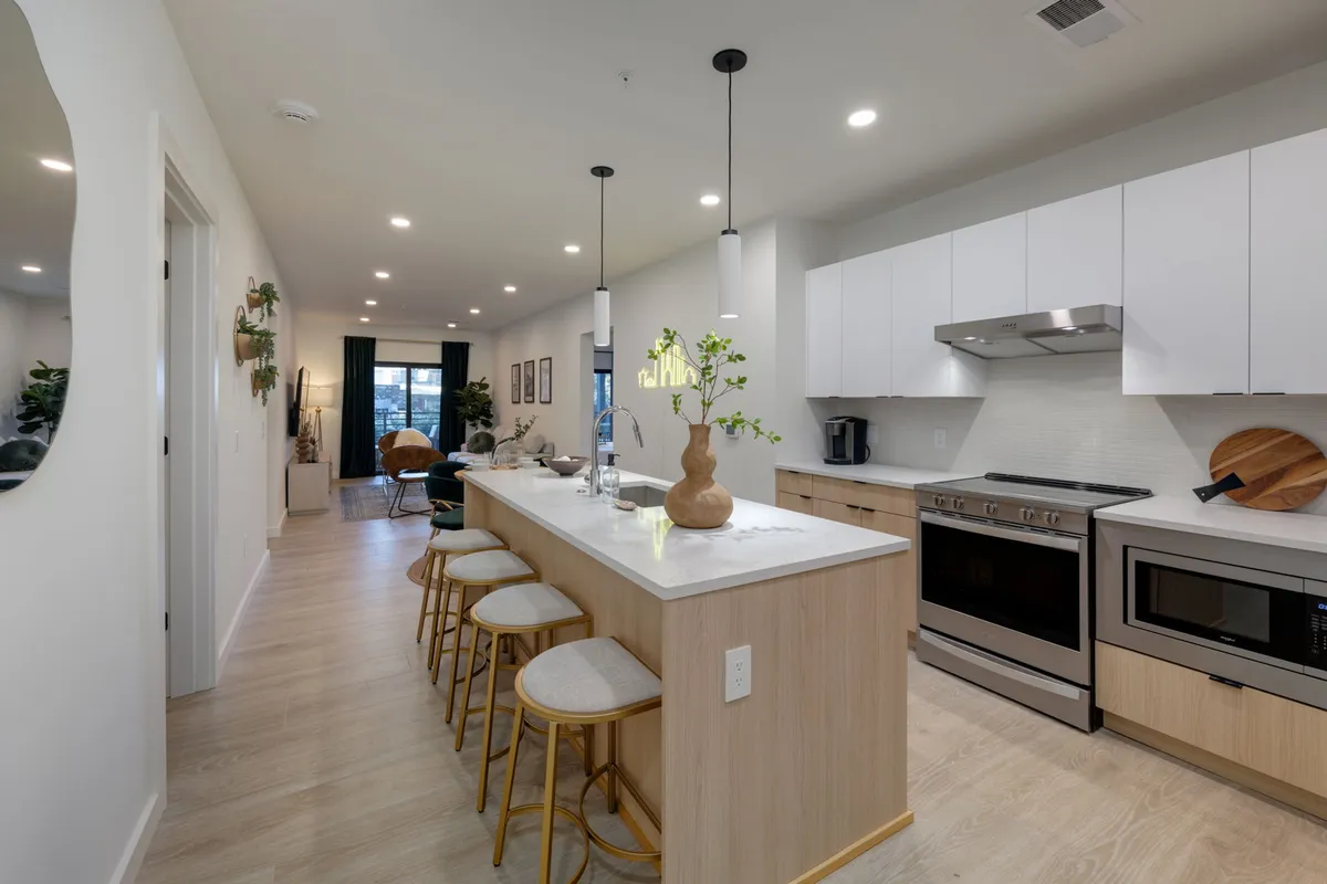 A bright, modern kitchen with a central island, pendant lights, and a stylish seating area. The space is equipped with all the essentials for cooking and casual dining, suggesting the presence of starter kits and a well-organized setup. The atmosphere is both cozy and functional, supporting extended stays.