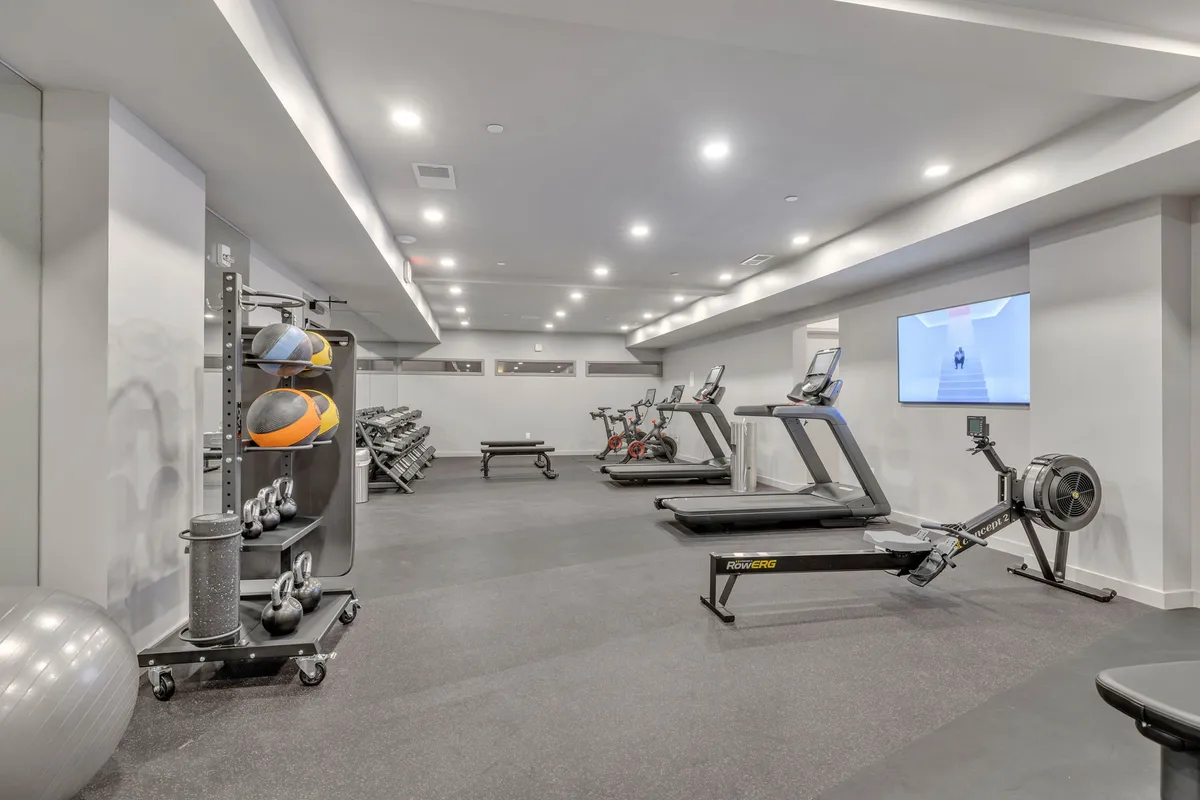 A well-equipped fitness center with treadmills, exercise bikes, a rowing machine, and medicine balls. The space is bright and organized, creating a motivational and active environment for maintaining fitness routines during a busy stay.